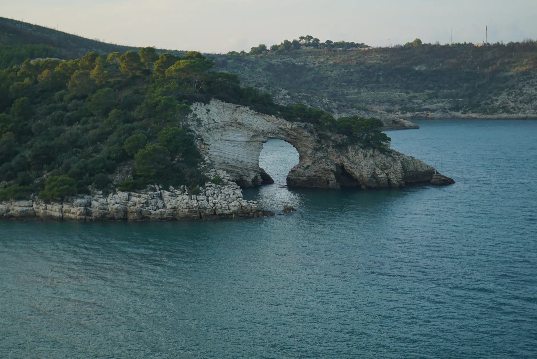 Stunning view of a natural rock arch along the Gargano coastline in Italy.